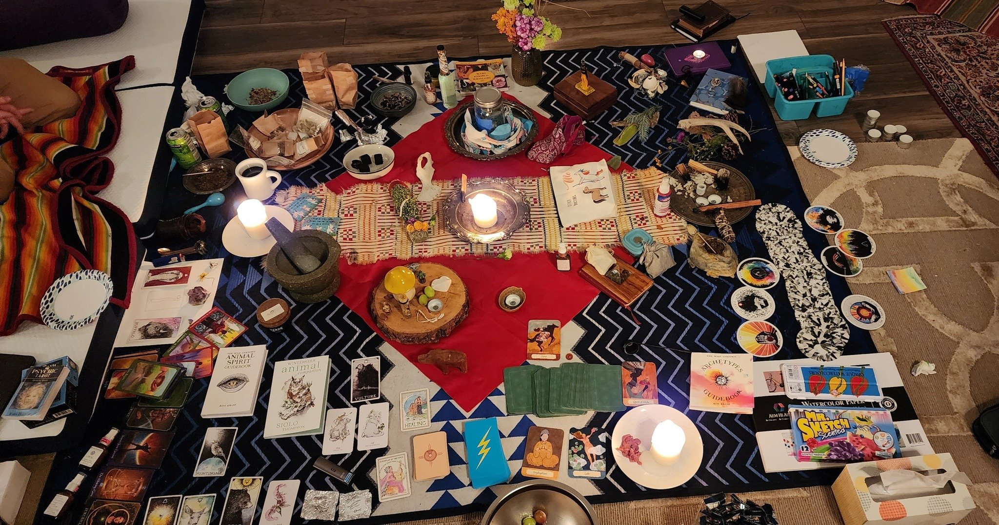 An altar with multiple tarot decks, candles, offerings, flowers, etc.